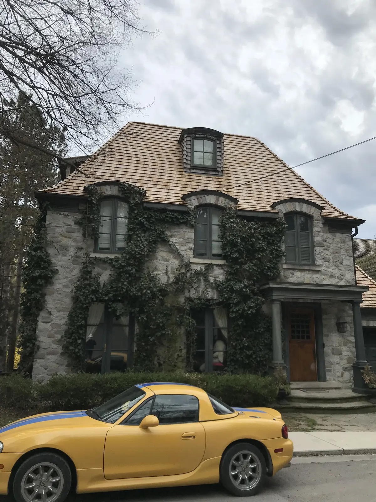 Stone chateau-style home with a cedar shake roof and dormers: slate, cedar & copper roofing by Eagle Roofing
