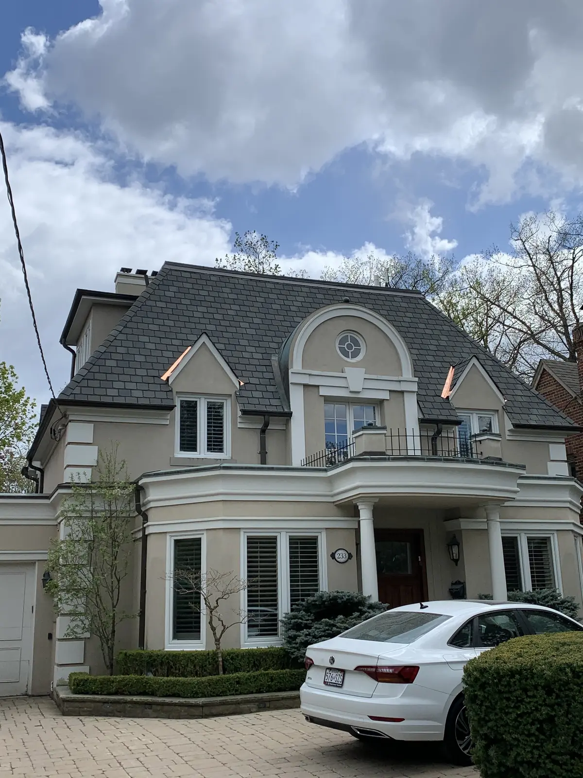 Classic two-storey home with a dark roof and a round dormer window: roof repair by Eagle Roofing