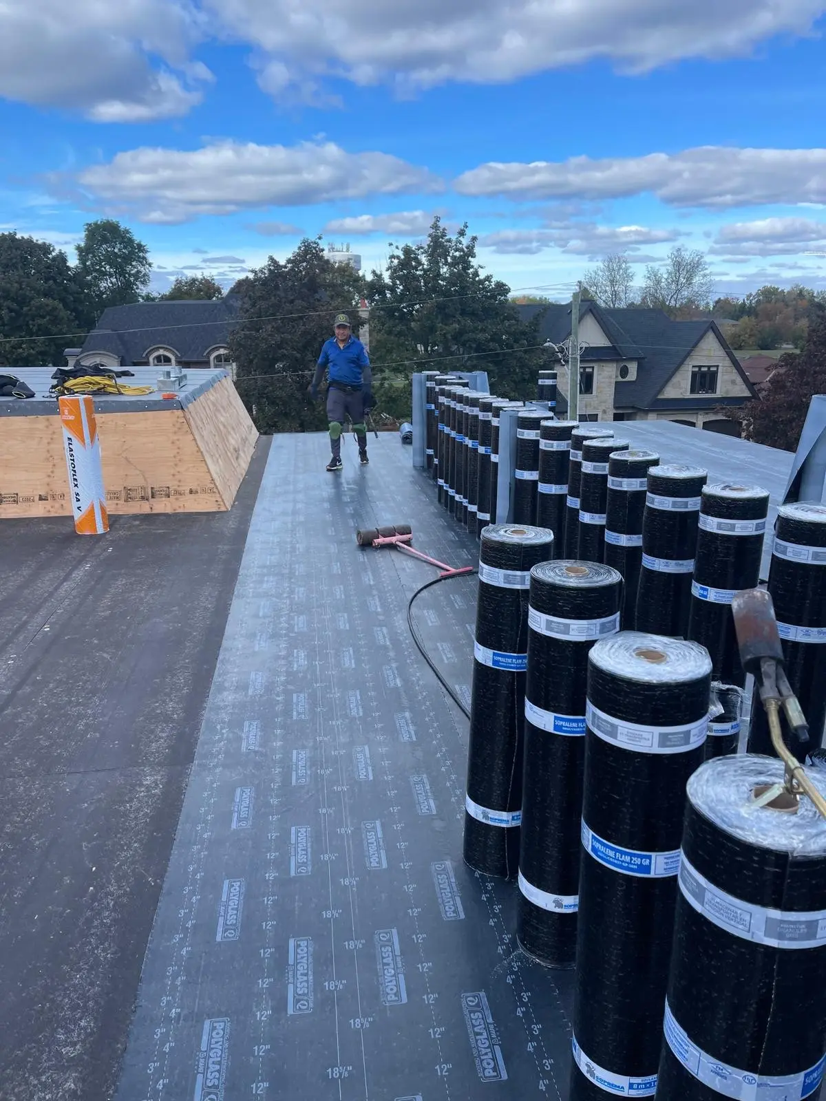 Rolls of roofing membrane lined up on a flat roof during installation: commercial roofing by Eagle Roofing